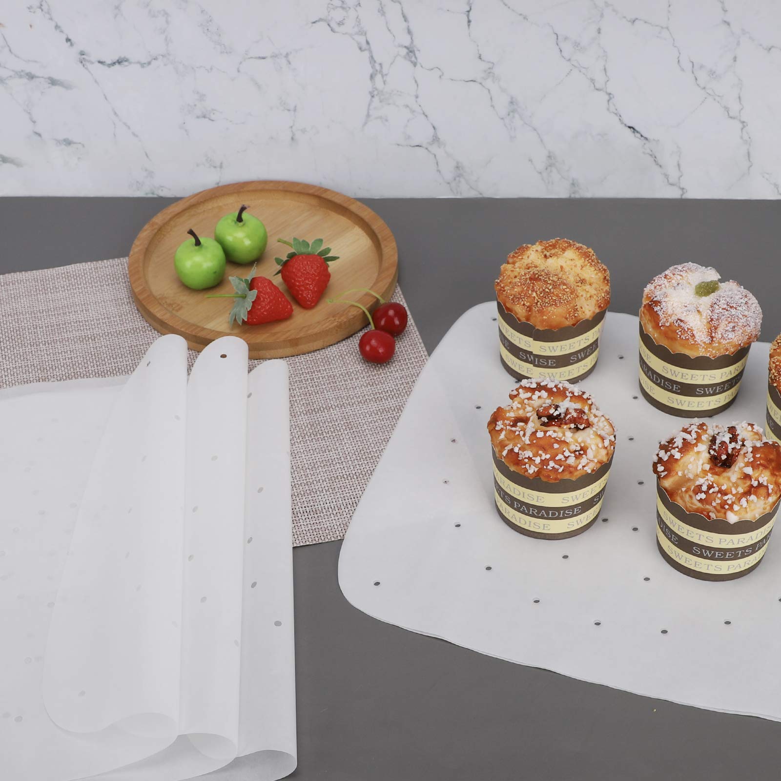 Muffins placed on square air fryer paper with holes beside rolled parchment liners