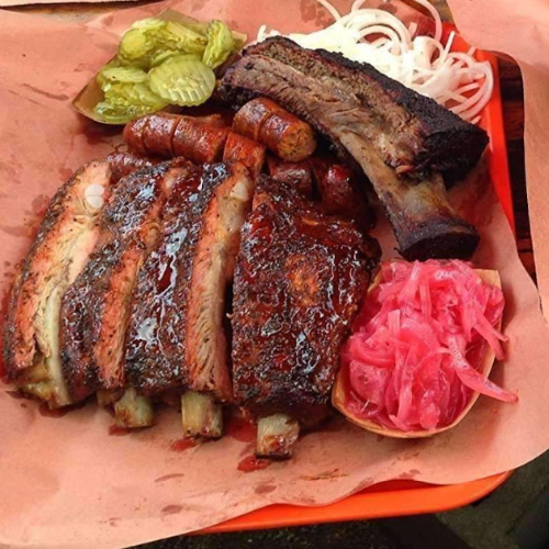 Sliced smoked meats arranged on pink butcher paper