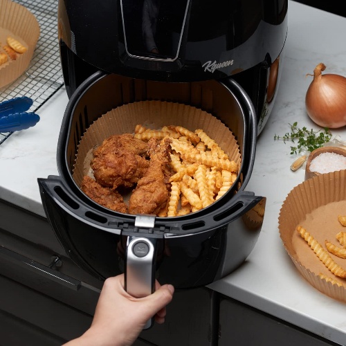 Air fryer with parchment paper lining and crispy food being cooked
