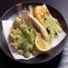 Various tempura-fried foods are placed on the tempura paper on the plate.